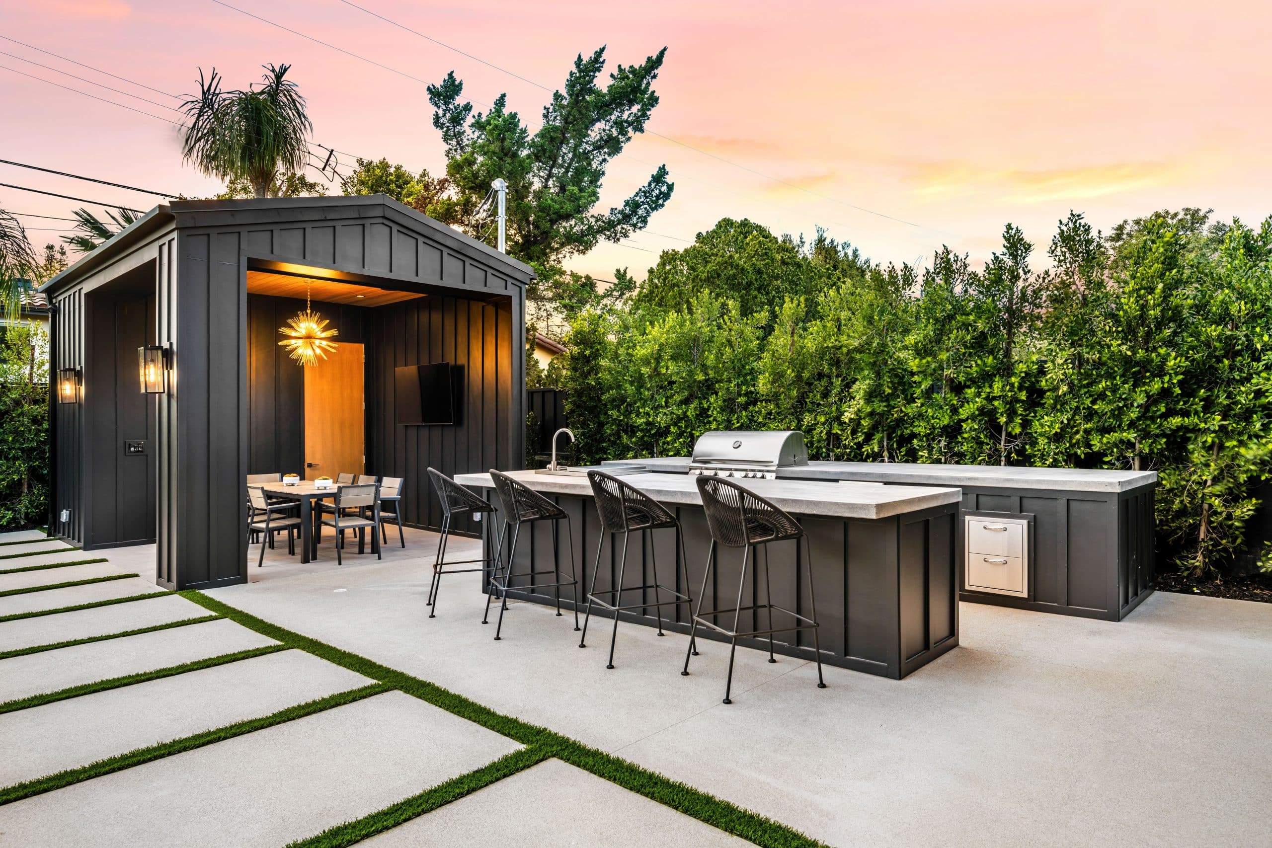 Modern Outdoor Kitchen And Dining Area At Sunset.
